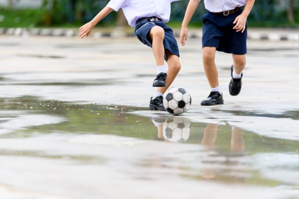 Boys in black shoe play football